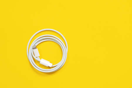 May 01, 2020, Rostov, Russia: White Apple wire lightning to usb type c, arranged in round skein on bright yellow background. Indoors, isolated, copy space.の写真素材