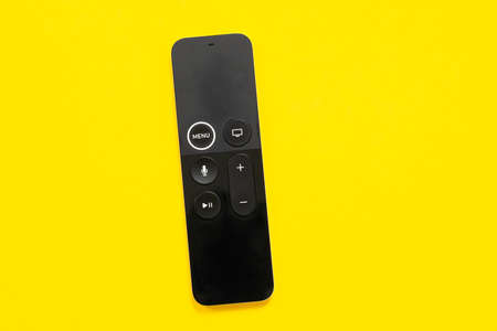 May 01, 2020, Rostov, Russia: New Apple TV modern stylish rechargeable touch swipe-to-select remote control for smart television console on yellow background, top view, copy space for advertisement.のeditorial素材