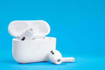 Rostov, Russia - July 06, 2020: Wireless headphones Apple AirPods Pro in opened charging case with active noise cancellation immersive sound, on blue background, copy space.のeditorial素材