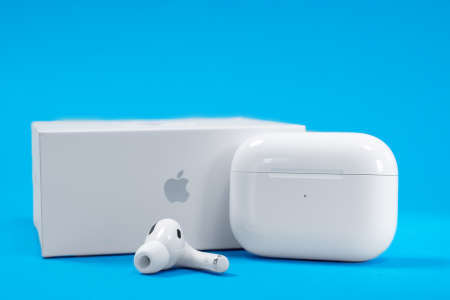 Rostov, Russia - July 06, 2020: New unpacked wireless headphones Apple AirPods Pro with rechargeable case and box on blue background, copy space for advertising text.のeditorial素材