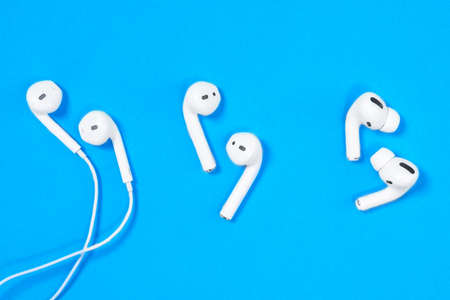 Rostov, Russia - July 06, 2020: Comparison of three generations of headsets for smartphones Apple wired headphone, wireless AirPods and new AirPods Pro on blue background, top view, copy space.のeditorial素材