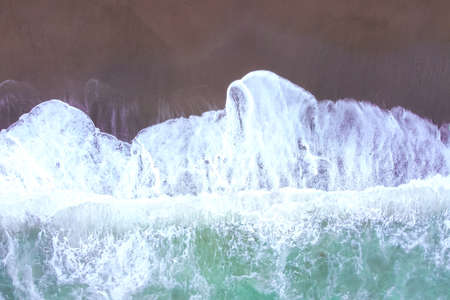 Top view from the drone on the stormy sea, waves and the beach.