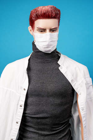 Mannequin man in medical coat and protective tissue respiratory mask on his face on blue background. Protection against threat of spread of virus. Reverse side of dangerous professionの写真素材