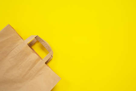 Paper recyclable eco friendly shopping bag on yellow background, top view copy space. Modern problem of global environmental pollution. The need for genuine ecology conscious consumptionの写真素材