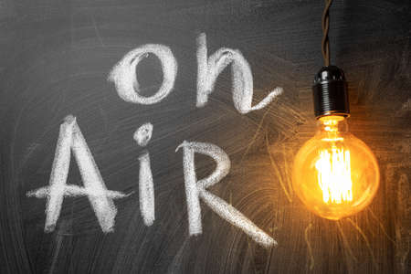 Media broadcasting warning sign ON AIR written in chalk on black wooden board in sound record...