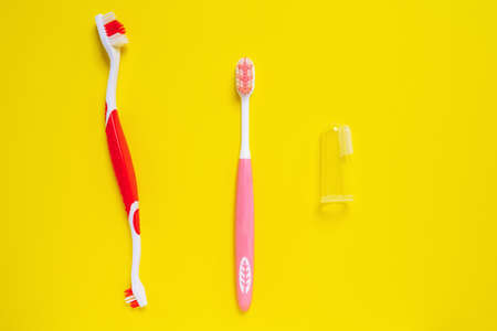 Different types of colored toothbrushes for people, dogs and pets isolated on yellow background....