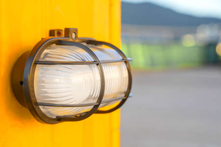 White modern lamp lantern on a yellow wall in a street parkingの写真素材