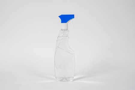 Plastic bottle with blue atomizer and transparent liquid or gel inside standing on white background. Disinfecting or cleansing treatment concept.の写真素材