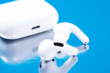 Rostov, Russia - July 06, 2020: Wireless headphones Apple AirPods Pro in opened charging case with active noise cancellation immersive sound, on blue background, copy space.のeditorial素材