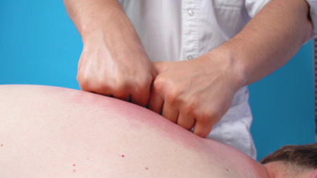 Professional chiropractor intensively massages and kneads tired and aching back and neck muscles of patient, close up. Health and rehabilitation therapy.の写真素材