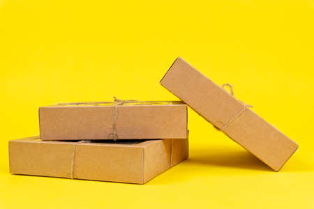 Cardboard recyclable boxes tied with a eco-friendly twine, for storage and delivery, lie in a pile on top of each other on yellow background, copy space.の写真素材