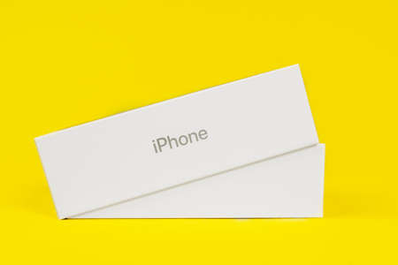 RUSSIA ROSTOV - MAY 29 2021: Half-closed box with new unpacked Apple iPhone lies on yellow background, side view, studio shot, copy space for advertising text.のeditorial素材
