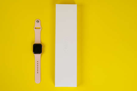 RUSSIA ROSTOV - MAY 29 2021: Apple Watch Series 6 with pink sand sport band on yellow background with display facing up, box are nearby, copy space. Smart device for active lifestyle.のeditorial素材
