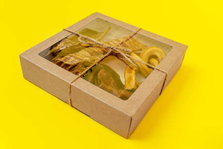 craft box with transparent top with tasty dried snacks for pets inside on yellow background, close up, top view, copy space for advertising text. Pet care. Pet supplies.の写真素材