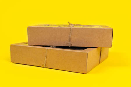 Cardboard recyclable boxes tied with a eco-friendly twine, for storage and delivery, on yellow background, copy space.の写真素材