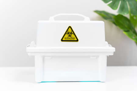 White plastic box with handle and sticker warning of threat of biological contamination is on the...