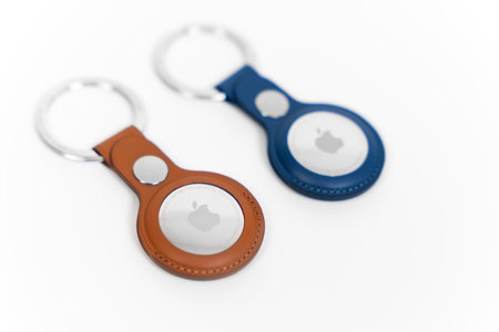 Rostov, Russia - April 04, 2022: Pair of Apple AirTags in leather key ring cases of Baltic blue and saddle brown colors lie on a white surface, close upのeditorial素材
