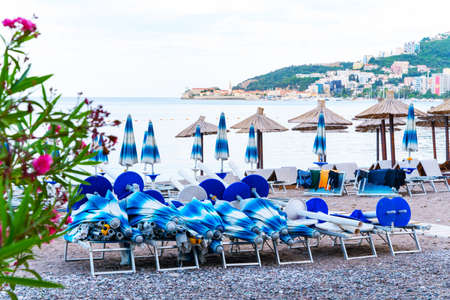 Umbrellas and sun loungers that have not yet been placed at the beginning of the day, or before the start of season at resort. Beautiful seascape on blurred backgroundの写真素材