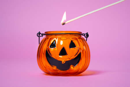 Small orange glass vessel in the shape of pumpkin, which is a festive jack-o-lantern. Someone...