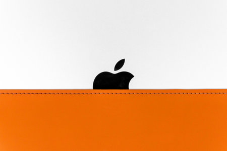 Rostov, Russia - April 04, 2022: Half of the brand logo is on Apple tech, partially hidden by a leather case, front view, close up. Creative commercial shot for stores.のeditorial素材