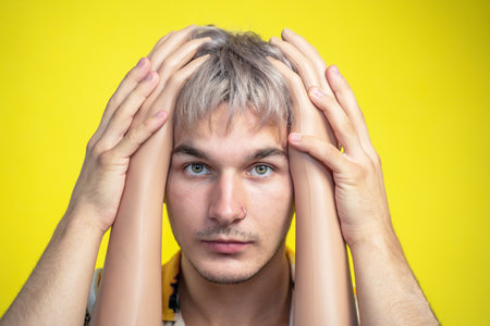Portrait young man holding hands of mannequin to head, gesture of psychological protection imposed artificial values, imposed stereotypes fake, Information overload, overthinking, frequency illusionの写真素材