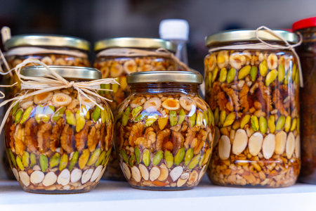 Close-up of glass jars display shelf delicious handmade eco dessert assorted nuts with honey. Craft sweets packaged for gift for immunity walnut hazelnut cashews filled with syrup. Farm Products Fairの写真素材