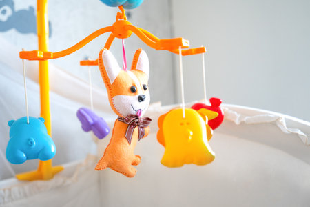 Bright plastic toy mobile for newborn is hung at headboard of baby bed. Orange, blue animals hang on spinning musical game mount. Interactive toys that develop senses. Children bedroom decorationsの写真素材