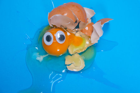 a whimsical display of a cracked eggshell with googly eyes on a vibrant blue backdrop, capturing a...