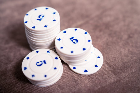 stacks of white casino chips featuring blue symbols arranged on a soft velvet surface, offering a luxurious gaming feel. perfect for themes of gambling, casino nights, and gamingの写真素材