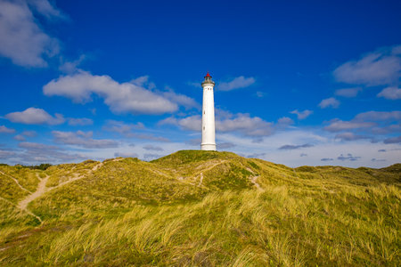 lighthouse Lyngvig Fyr on the coast of Denmark with sunny cloudy blue skyの写真素材