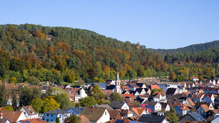 view from above of the town of Dahn with the cemetery and church in sunshine and autumnal forestの写真素材