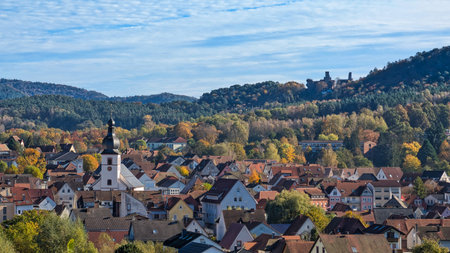 view from above of the town of Dahn with the church in sunshine and autumnal forestの写真素材