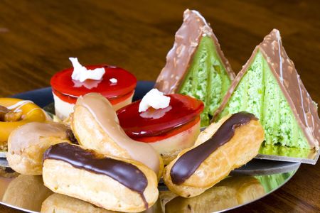 Assortment of freshly baked cakes on silver reflective plate on wooden table
