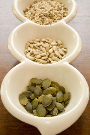 Closeup of a small white bowl with pumpkin, sesame and sunflower seedsの写真素材