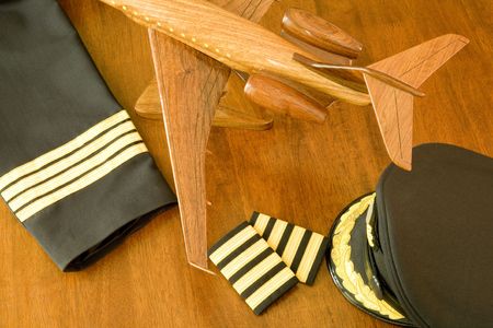 A pilot's uniform, cap and a wooden aircraft on a tableの写真素材
