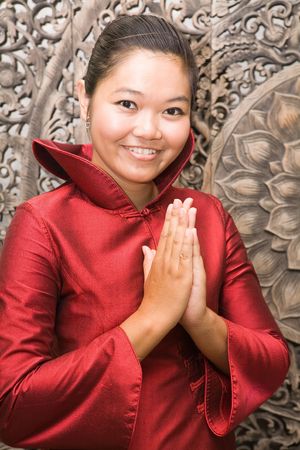Young Thai woman in red silk dress greetingの写真素材