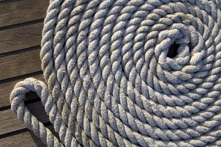 White rope rolled up in a circle on a wooden surfaceの写真素材
