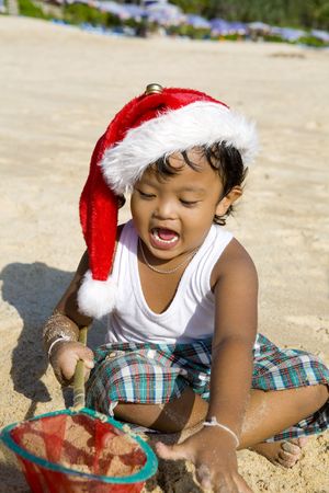 Little Thai boy with christmas hat playing on beachの写真素材