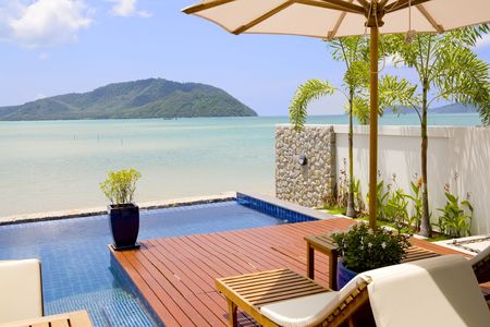 A beautiful decorated veranda with deck chairs, umbrella and a view of the ocean and islandsの写真素材
