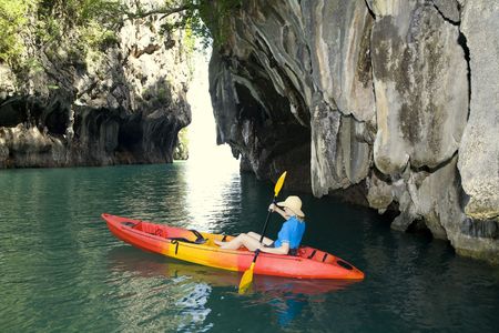 Woman on a canoe paddling past a breakthtaking islandの写真素材