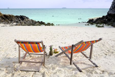Two folding chairs on a white beach with a beautiful viewの写真素材