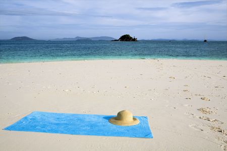 A turquoise towel and sun hat on a white beach. copy spaceの写真素材