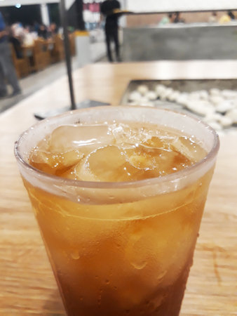 Iced cola in plastic cup on wood table, stock photo