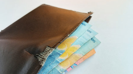 Close up of Thai banknotes in brown wallet on white background.