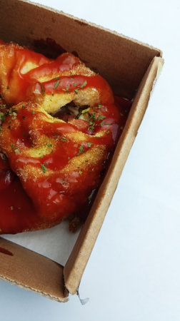 Paprika baked in tomato sauce with parsley in a cardboard box