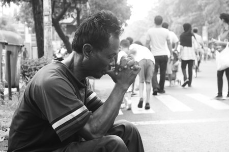 Black and white portrait of an old man sitting while praying, Surakarta, Indonesia.