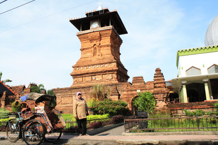 Front view of the Mosque Tower in Kudus with a parked rickshaw, Indonesia.のeditorial素材
