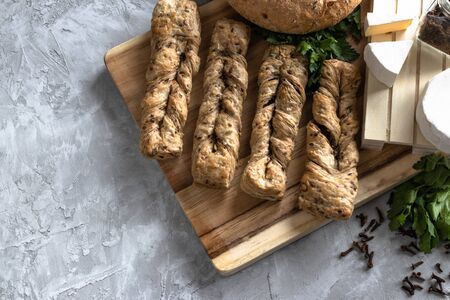 Brie cheese with fresh bread and parsley on wooden board and gray concrete