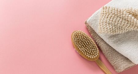 Body brush for anti-cellulite massage and skin treatment with soft towels on pink background. Lay out design with copy space. Cactus long handle exfoliating brush for body careの写真素材