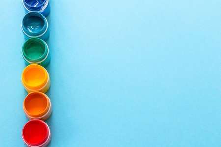 paints in jars in row on blue background in top viewの写真素材